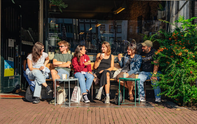 Group of friends chatting outside a cafe. Young people enjoying a sunny day in Amsterdam.