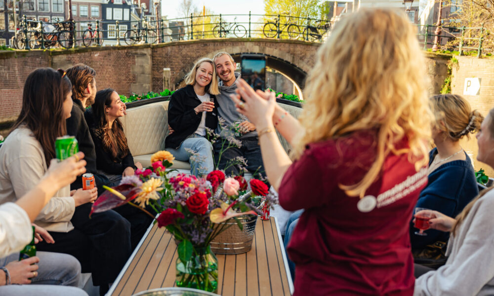 Friends on a canal boat enjoying drinks. A woman taking a photo.