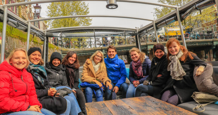 Smiling tourists on a boat tour in Amsterdam. They are enjoying the city sights.