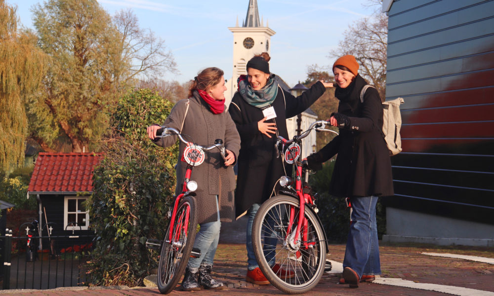 Amsterdamliebe Fahrradtour Noord Tourteilnehmer stehen mit Tourguide neben einem Häuschen