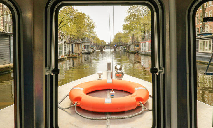A view of a canal from a boat with an orange life preserver.