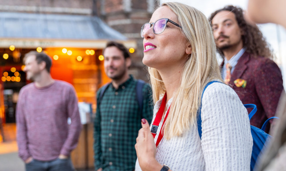 Tourguide Theresa von Amsterdamliebe steht mit Tourteilnehmern auf dem Nieuwmarkt