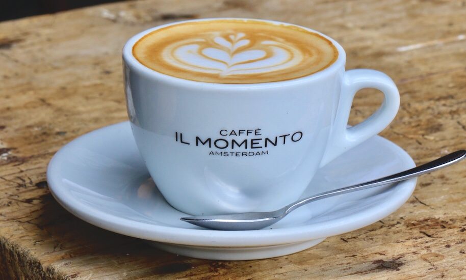 Leckerer Kaffee von Il Momento in einer weißen Tasse mit Unterteller und Silberlöffel