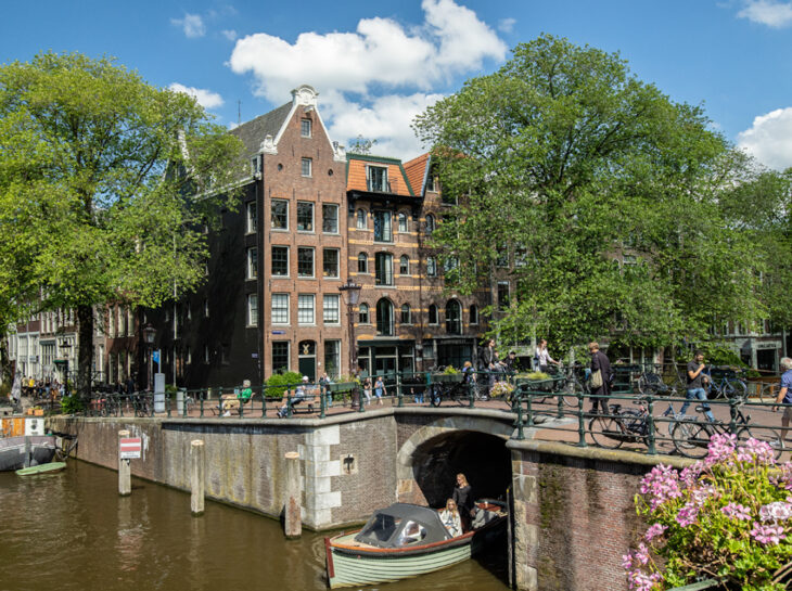A boat navigates under a bridge in Amsterdam. The city is known for its charming canals.
