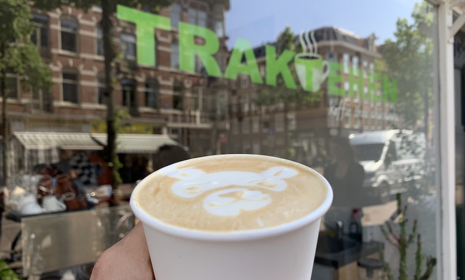 A to-go coffee with a bear pattern in front of the Trakteren Café