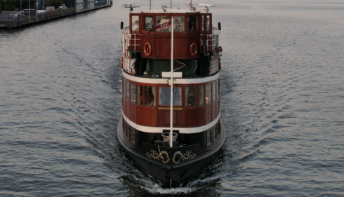 A double-decker boat on a serene Amsterdam canal. A perfect way to explore the city.