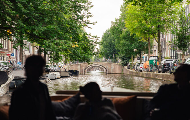 People on a boat looking at a canal bridge. A typical Amsterdam city view.