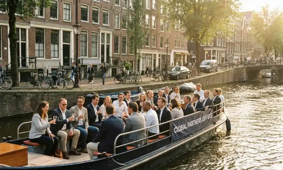 Diverse business professionals networking on canal boat cruise through Amsterdam's historic waterways at golden hour.