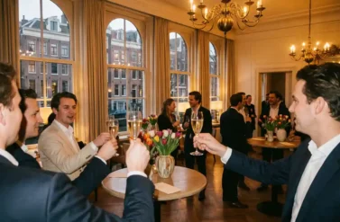 Business professionals raising champagne glasses in toast at elegant Amsterdam canal-side venue with historic views