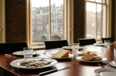 Mahogany boardroom table with Dutch herring, aged Gouda cheese, and stroopwafels in Amsterdam canal house setting